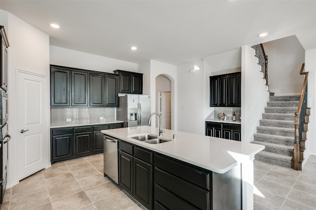 kitchen featuring backsplash, a center island with sink, sink, light tile patterned floors, and appliances with stainless steel finishes