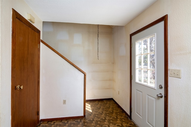 entryway with dark parquet floors and a textured ceiling