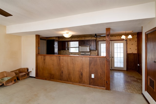 kitchen featuring kitchen peninsula, carpet flooring, decorative light fixtures, and ceiling fan with notable chandelier