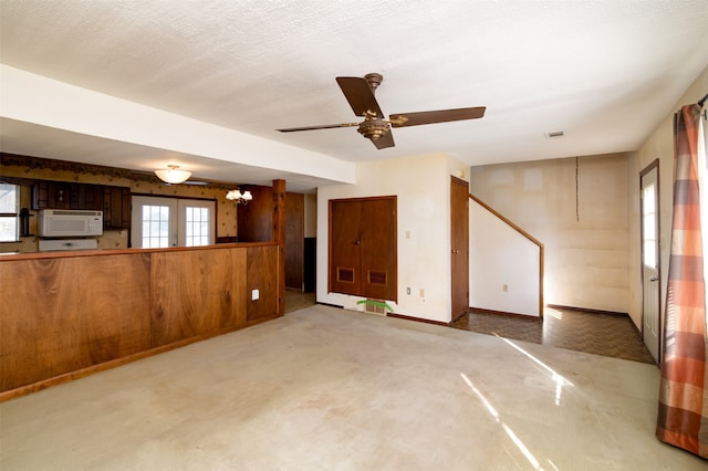 unfurnished living room with carpet flooring, a textured ceiling, and ceiling fan with notable chandelier