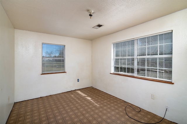 unfurnished room with a textured ceiling