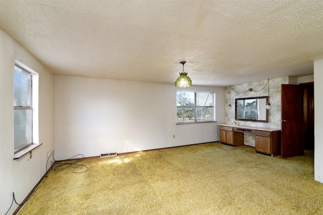 kitchen with sink, light colored carpet, pendant lighting, and a textured ceiling