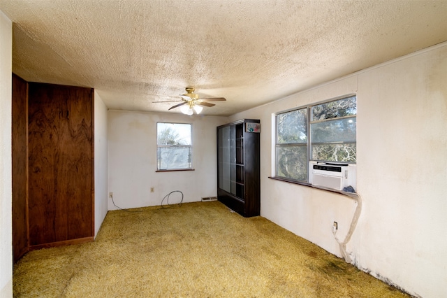 empty room with ceiling fan, light colored carpet, and a textured ceiling