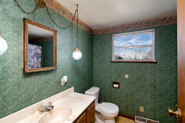 bathroom with vanity, toilet, and a textured ceiling