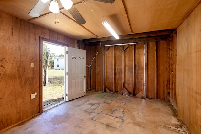 interior space featuring ceiling fan and wooden walls