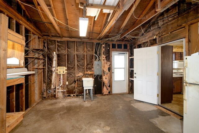 basement with electric panel and white fridge