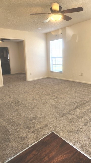 carpeted spare room featuring ceiling fan and a textured ceiling