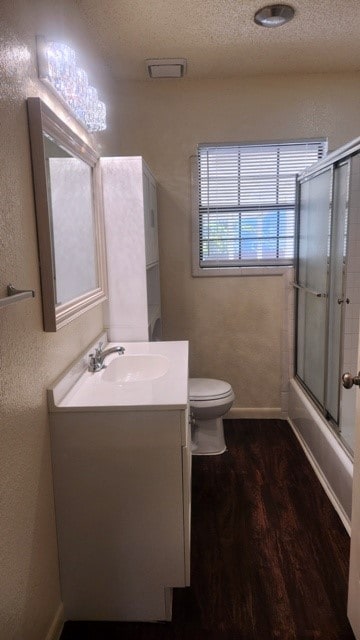 full bathroom featuring enclosed tub / shower combo, a textured ceiling, toilet, vanity, and hardwood / wood-style flooring