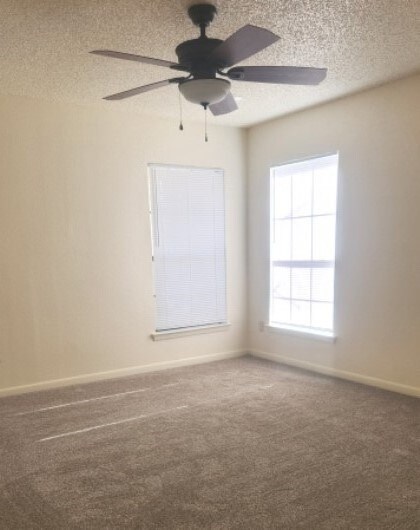 carpeted spare room with a textured ceiling and ceiling fan