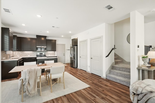 kitchen featuring appliances with stainless steel finishes, dark hardwood / wood-style flooring, backsplash, dark brown cabinets, and sink