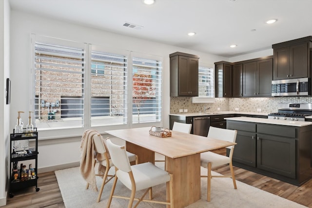 kitchen featuring a center island, light hardwood / wood-style flooring, tasteful backsplash, dark brown cabinetry, and stainless steel appliances