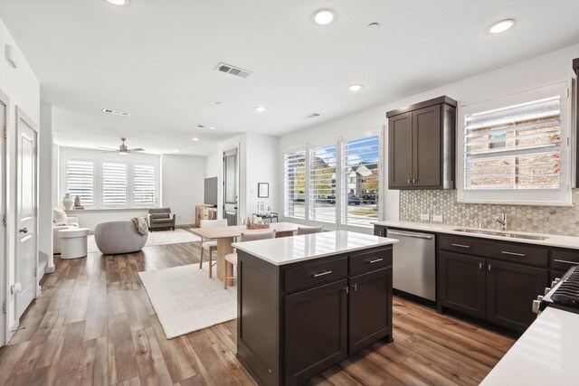 kitchen featuring stainless steel dishwasher, ceiling fan, decorative backsplash, a kitchen island, and wood-type flooring