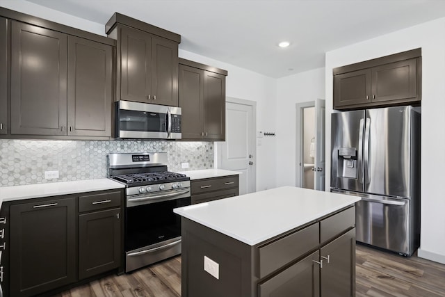 kitchen with tasteful backsplash, dark brown cabinets, stainless steel appliances, dark hardwood / wood-style floors, and a kitchen island