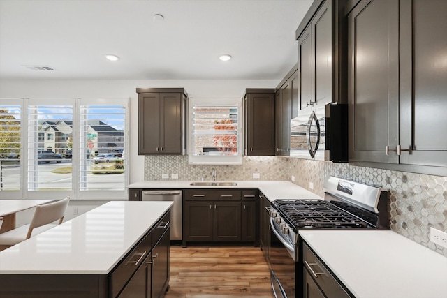 kitchen featuring sink, appliances with stainless steel finishes, tasteful backsplash, light hardwood / wood-style floors, and dark brown cabinetry