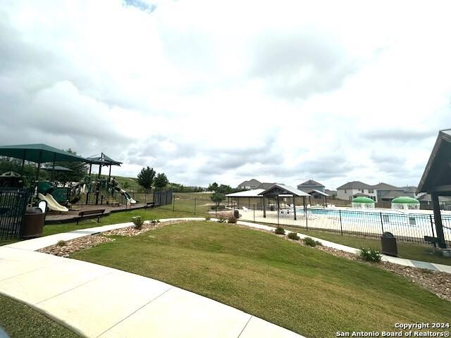 exterior space featuring a playground, a lawn, and a pool