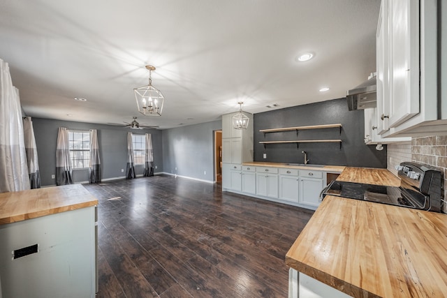 kitchen featuring ceiling fan with notable chandelier, black range with electric cooktop, pendant lighting, butcher block countertops, and white cabinetry