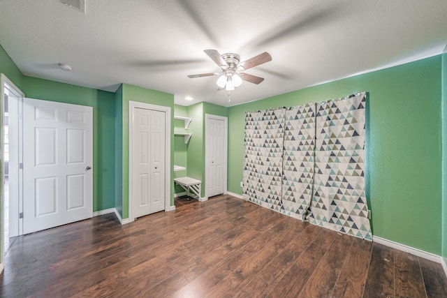 unfurnished bedroom with ceiling fan, dark hardwood / wood-style flooring, and a textured ceiling