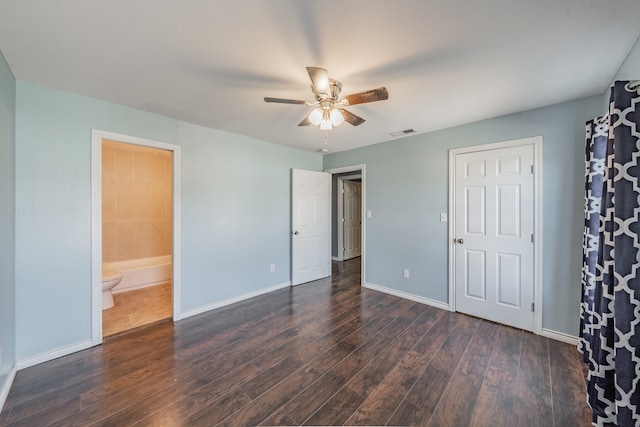 unfurnished bedroom with dark hardwood / wood-style floors, ensuite bath, and ceiling fan