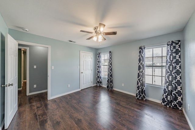 unfurnished bedroom with ceiling fan, dark hardwood / wood-style floors, and multiple windows