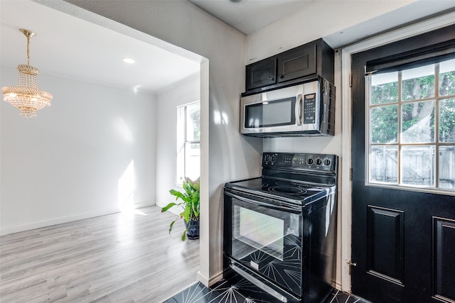 kitchen featuring an inviting chandelier, light hardwood / wood-style flooring, a wealth of natural light, and black electric range