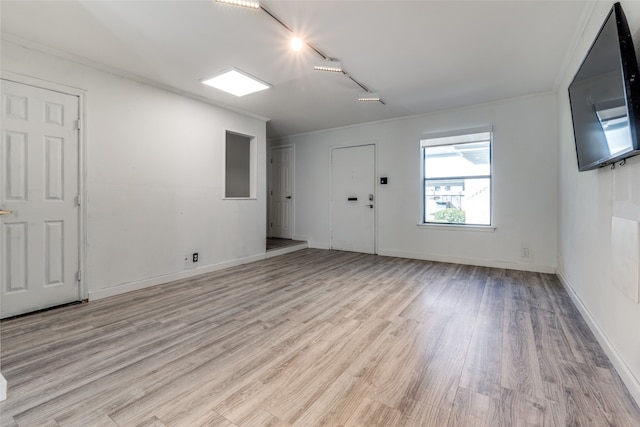 empty room with light wood-type flooring and ornamental molding