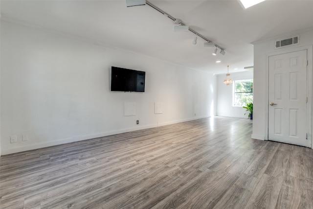 unfurnished living room featuring light hardwood / wood-style flooring, rail lighting, an inviting chandelier, and ornamental molding