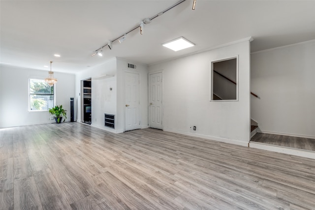 unfurnished living room featuring light wood-type flooring, rail lighting, and ornamental molding