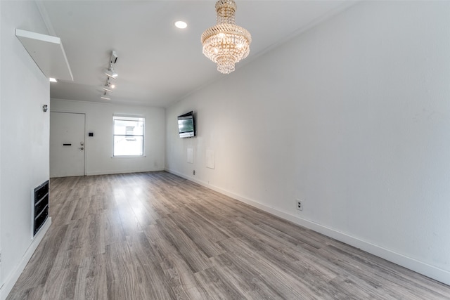 unfurnished living room featuring a chandelier, heating unit, and light hardwood / wood-style flooring