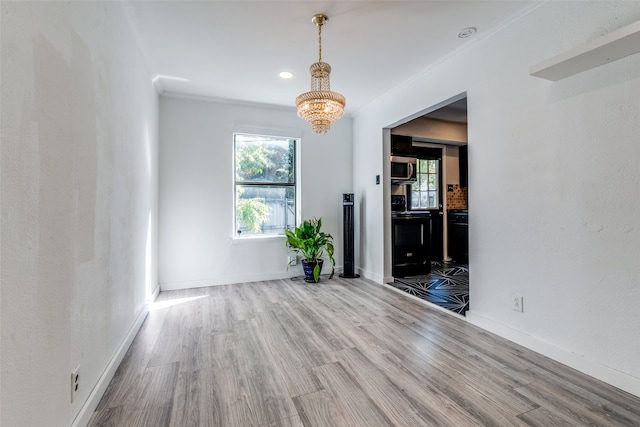 empty room with hardwood / wood-style floors, an inviting chandelier, and plenty of natural light