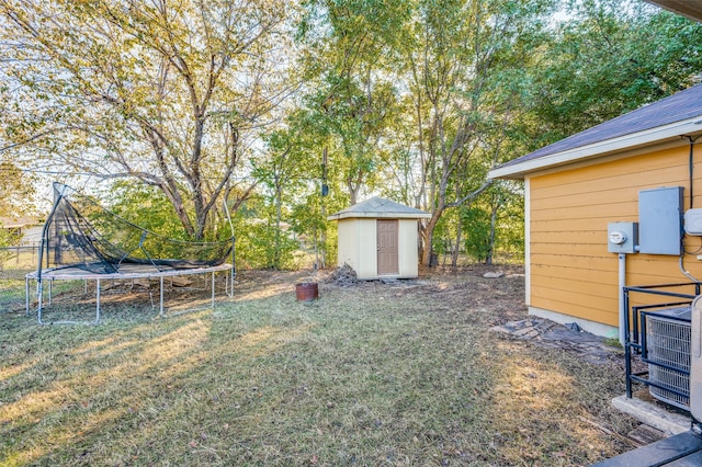 view of yard with central AC unit, a storage unit, and a trampoline