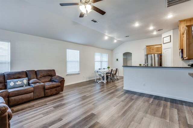 living room with ceiling fan, lofted ceiling, and light hardwood / wood-style flooring