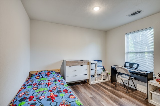 bedroom with a textured ceiling and hardwood / wood-style flooring