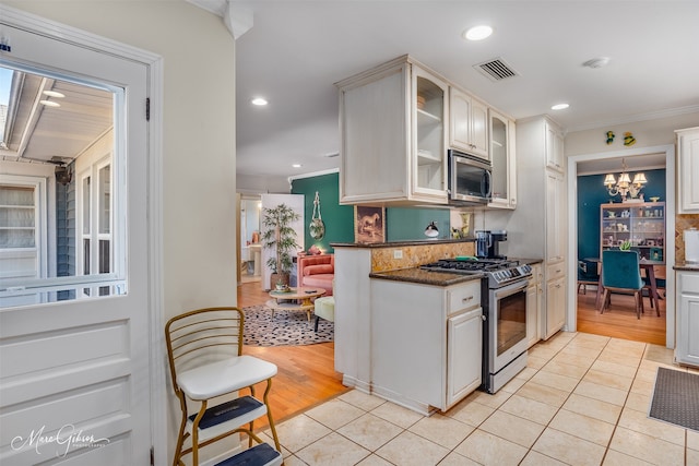 kitchen with dark stone counters, light hardwood / wood-style flooring, decorative backsplash, white cabinetry, and stainless steel appliances