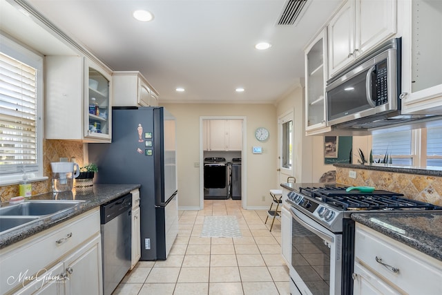 kitchen with appliances with stainless steel finishes, white cabinetry, and washer and clothes dryer