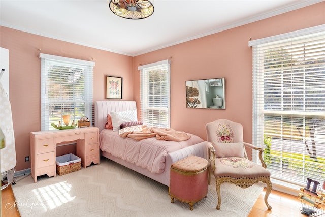 bedroom featuring multiple windows, light wood-type flooring, and ornamental molding