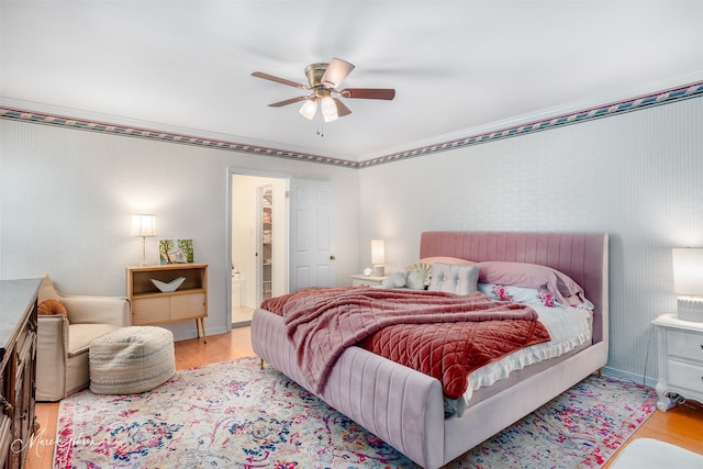 bedroom with ceiling fan, ensuite bath, and light hardwood / wood-style flooring