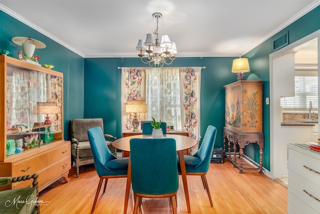 dining area featuring light hardwood / wood-style floors, an inviting chandelier, crown molding, and sink