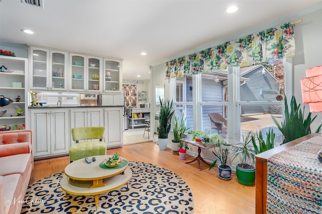 sitting room with ornamental molding and light wood-type flooring