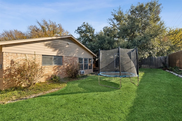 rear view of property with a trampoline and a yard