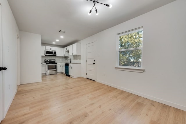 unfurnished living room with a notable chandelier and light hardwood / wood-style floors