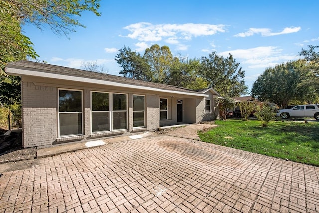 back of property with a yard and a patio