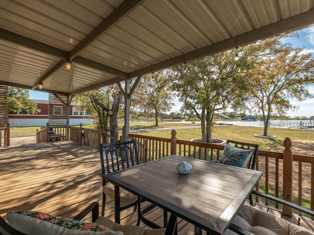 deck featuring outdoor dining area, a water view, and a yard