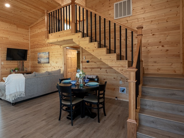 dining space featuring hardwood / wood-style floors, high vaulted ceiling, wood walls, and wood ceiling