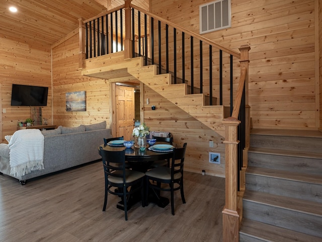 dining area with visible vents, wood finished floors, stairway, wooden walls, and wood ceiling