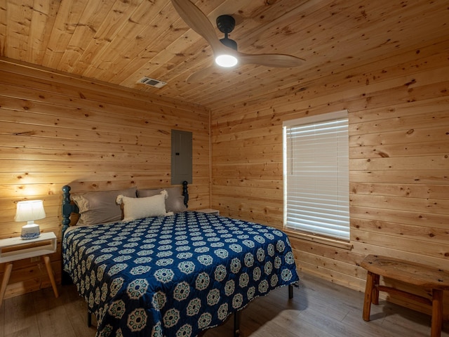 bedroom featuring electric panel, wood-type flooring, wood ceiling, and wood walls