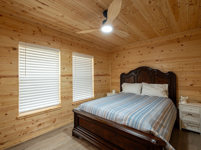 bedroom featuring ceiling fan, wood walls, light wood-type flooring, and wooden ceiling