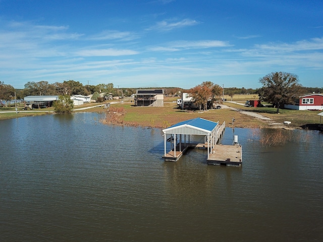 view of dock with a lawn and a water view