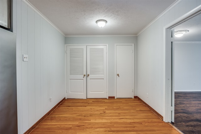 hall featuring a textured ceiling, light hardwood / wood-style floors, and crown molding