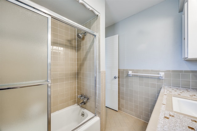 bathroom featuring shower / bath combination with glass door, sink, and tile walls