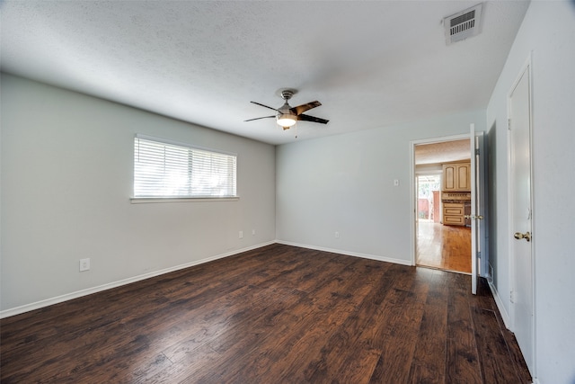 unfurnished room with a textured ceiling, ceiling fan, and dark wood-type flooring